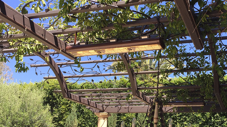 Two heaters hanging from a wooden trellis